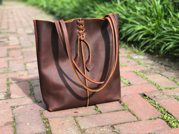 Tall brown leather tote with middle stitch and leaf tassels