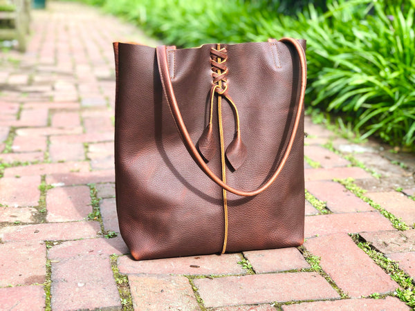 Tall brown leather tote with middle stitch and leaf tassels