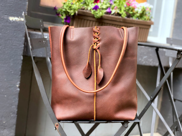 Tall brown leather tote with middle stitch and leaf tassels