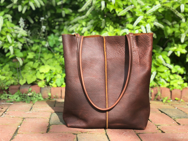 Tall brown leather tote with middle stitch and leaf tassels