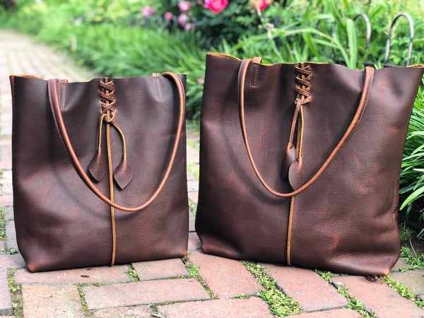 Tall brown leather tote with middle stitch and leaf tassels