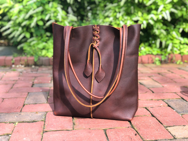 Tall brown leather tote with middle stitch and leaf tassels