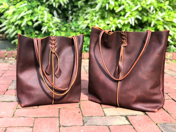 Tall brown leather tote with middle stitch and leaf tassels